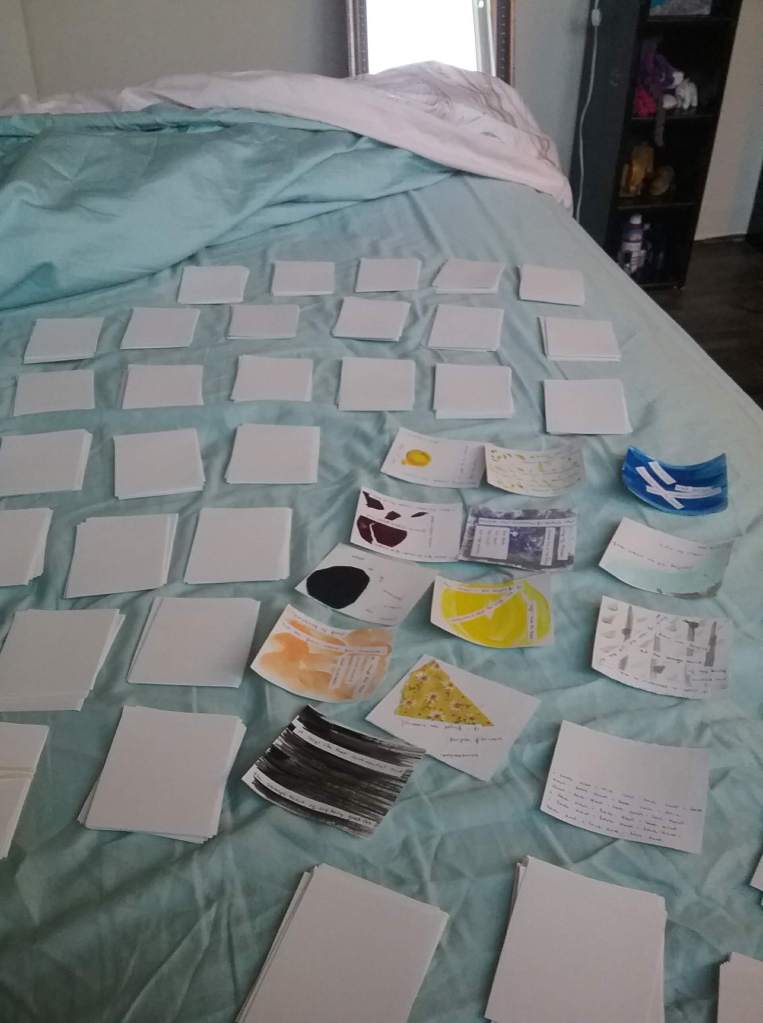 small cards are scattered on a bed - many are white and some are painted in vibrant colors. each card will eventually be painted to include in this mail project.