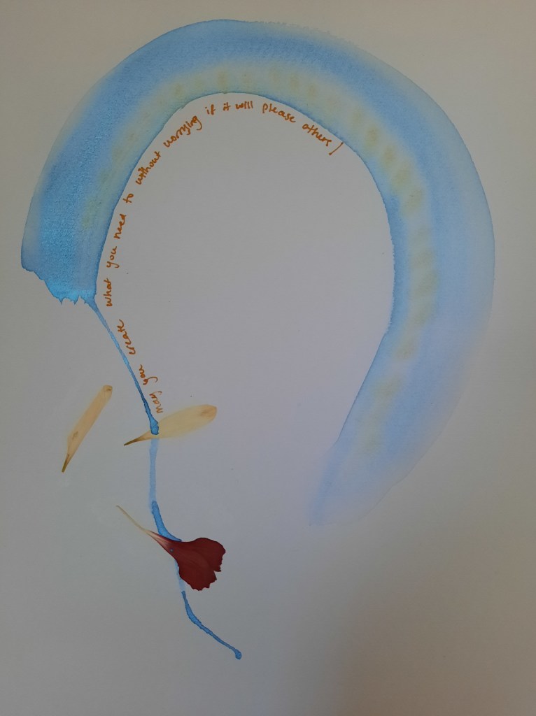 blue and green metallic watercolor paint across the top and sides of white paper, with three flower petals. there is writing that says "may you create what you need to without worrying if it will please others."